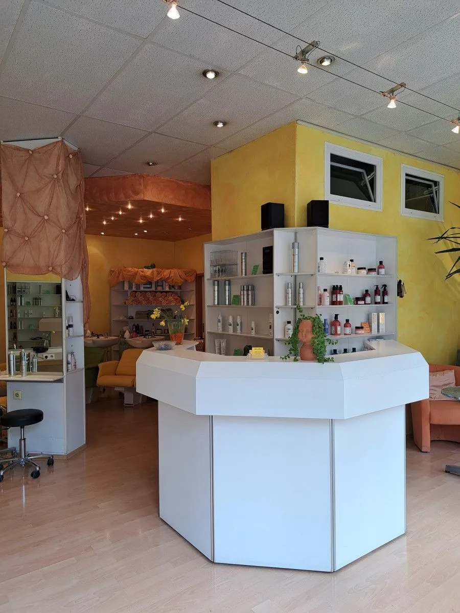 Empfangstresen im Inneren von Silke's Salon mit gelben Wänden und Produktregalen